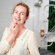 portrait-woman-with-braces-demonstrating-interdental-brushing