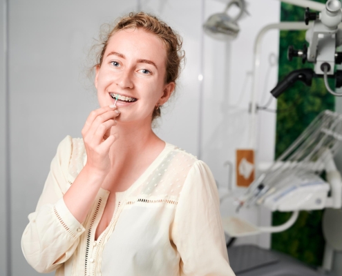 portrait-woman-with-braces-demonstrating-interdental-brushing